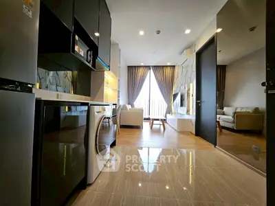 Modern open-plan living room with sleek kitchen and cozy seating area, featuring large windows and stylish decor.