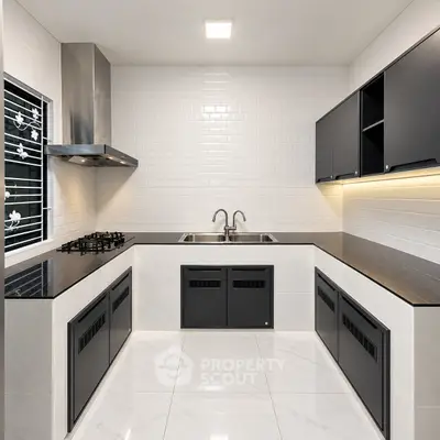 Modern kitchen with sleek black cabinetry and gas stove in a stylish open layout.