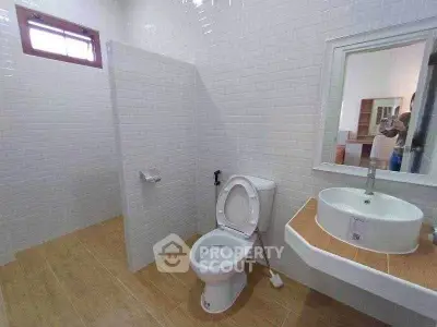 Spacious modern bathroom with white tiles and wooden flooring