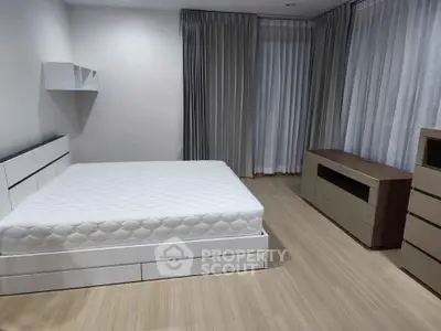 Spacious bedroom with modern furniture and large windows for natural light.