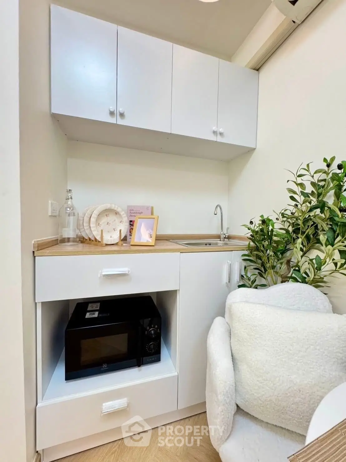 Cozy kitchen with modern white cabinets and microwave, perfect for compact living.