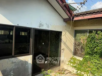 Charming fixer-upper with potential, featuring overgrown garden and rustic exterior, ideal for renovation enthusiasts.