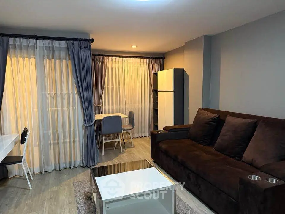 Modern living room with cozy sofa and dining area, featuring elegant curtains and stylish decor.