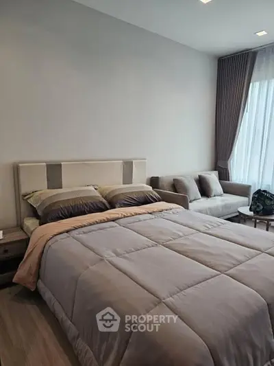 Modern bedroom with cozy bed and stylish sofa, perfect for relaxation.