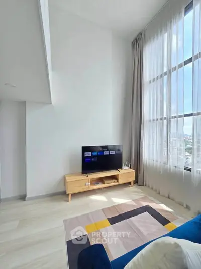 Bright living room with high ceilings and large windows offering city views.