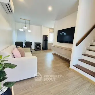 Modern living room with sleek design, featuring a large TV and stylish furniture.