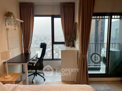 Modern bedroom with city view and balcony access, featuring a study desk and washing machine.