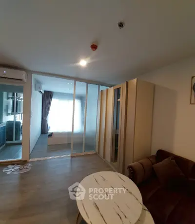 Modern apartment interior with cozy living area and glass partitioned bedroom.