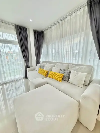 Spacious living room with modern white sofa and large windows for natural light.