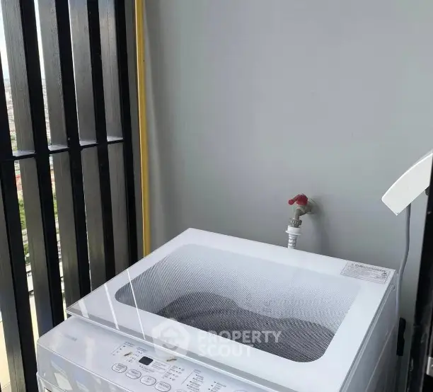 Modern balcony with washing machine and sleek railing design.