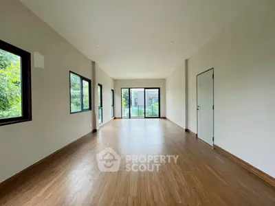 Spacious empty room with large windows and wooden flooring