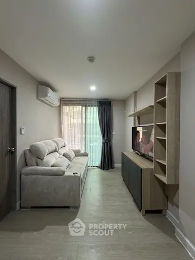 Modern living room with cozy sofa and entertainment unit, featuring elegant curtains and air conditioning.