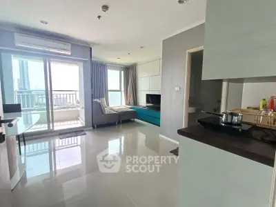 Modern living room with balcony and city view, featuring sleek furniture and open layout.