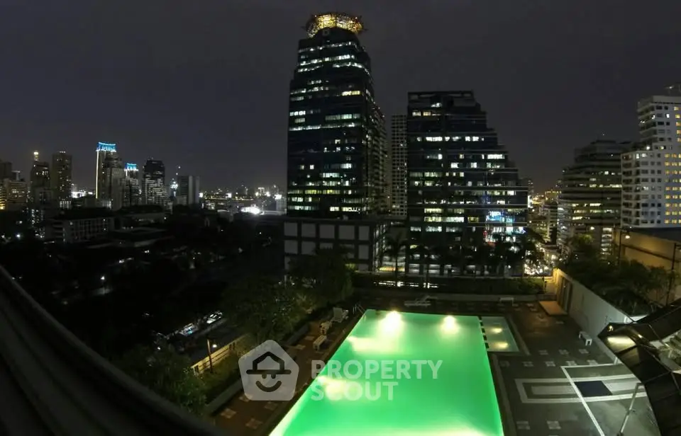 Stunning night view of city skyline with illuminated pool in modern apartment complex.