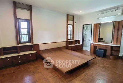 Spacious bedroom with wooden flooring and built-in furniture