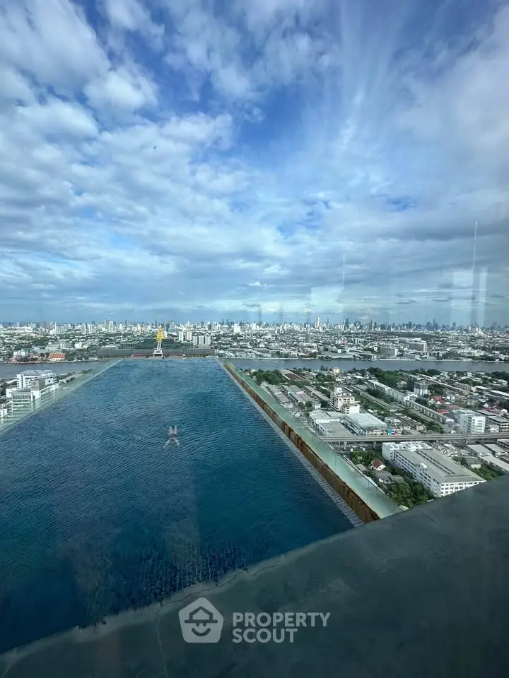 Stunning rooftop infinity pool with panoramic city skyline view under a vibrant blue sky.