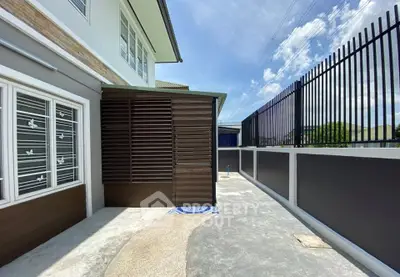 Modern exterior with sleek fencing and spacious walkway under clear skies.