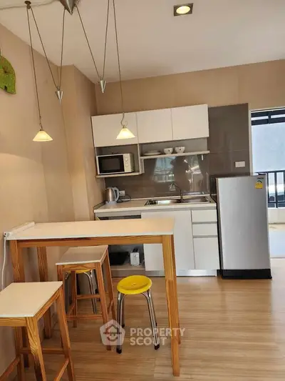 Modern kitchen with sleek cabinetry, breakfast bar, and stainless steel appliances in a cozy apartment.