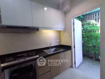 Modern kitchen with open door leading to lush garden area
