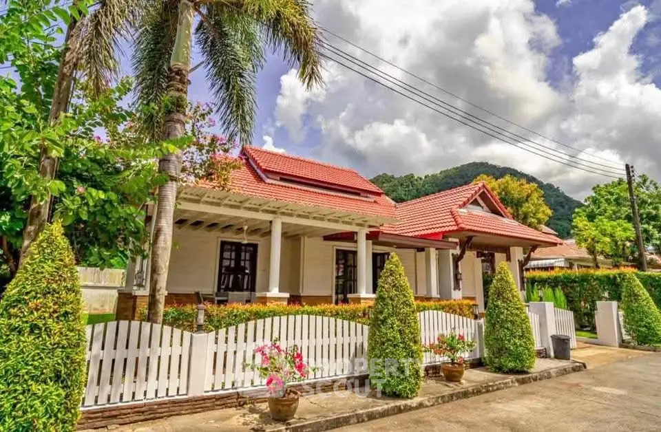 Charming suburban house with red roof and lush garden, perfect for family living.