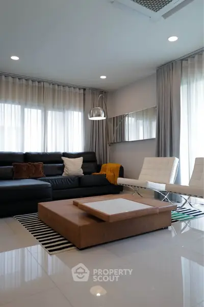 Modern living room with sleek furniture and ample natural light, perfect for relaxation and entertainment.
