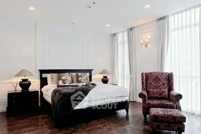 Luxurious bedroom with elegant decor and natural light, featuring a plush armchair and stylish bedding.