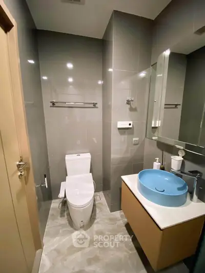Modern bathroom with sleek fixtures and stylish blue basin in a contemporary apartment.