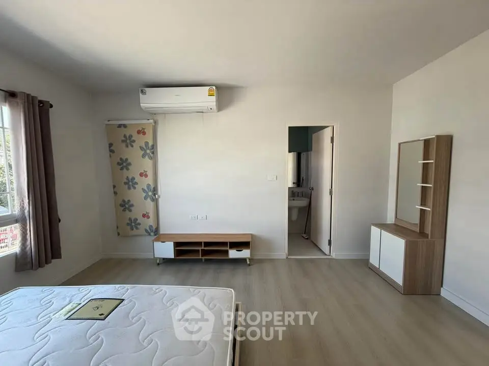 Spacious bedroom with modern decor and natural light, featuring air conditioning and stylish furniture.