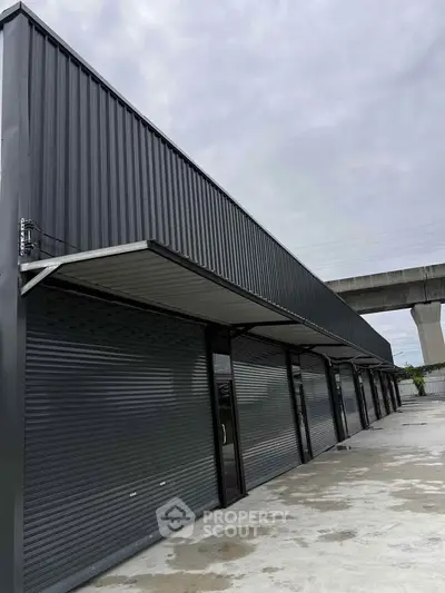 Modern commercial building with sleek metal facade and multiple shutter doors.