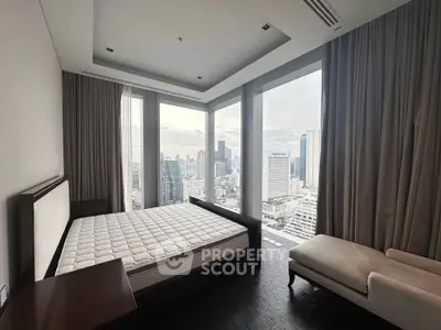 Luxurious bedroom with panoramic city views and elegant furnishings in a high-rise apartment.