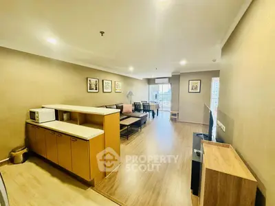 Spacious living room with modern decor and open layout, featuring a cozy seating area and large windows.