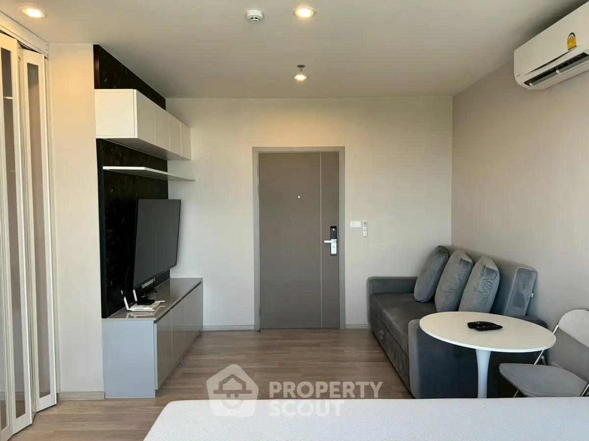 Modern living room with sleek furniture and wall-mounted TV in a cozy apartment.
