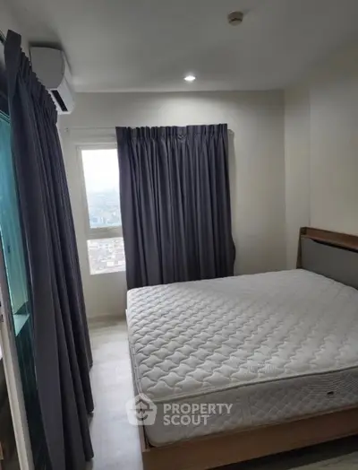 Cozy bedroom with large window and modern furnishings, perfect for relaxation.