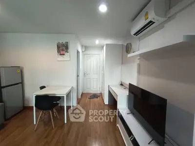 Modern living room with sleek furniture and wooden flooring, featuring a TV and dining area.