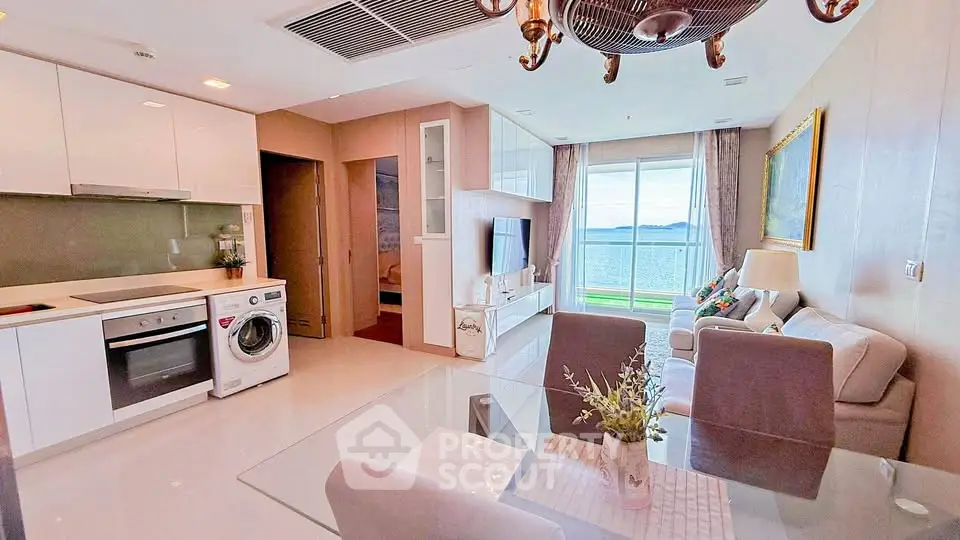 Modern open-plan living room with sea view, featuring elegant decor and integrated kitchen appliances.