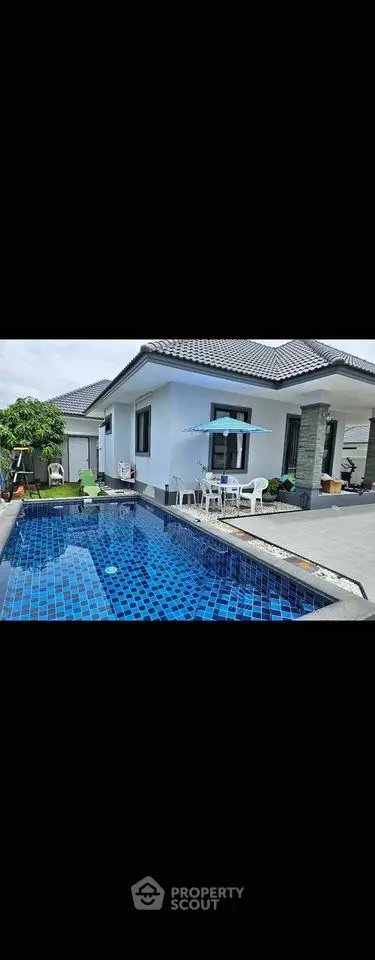 Luxurious modern villa with private blue-tiled swimming pool and spacious outdoor patio.