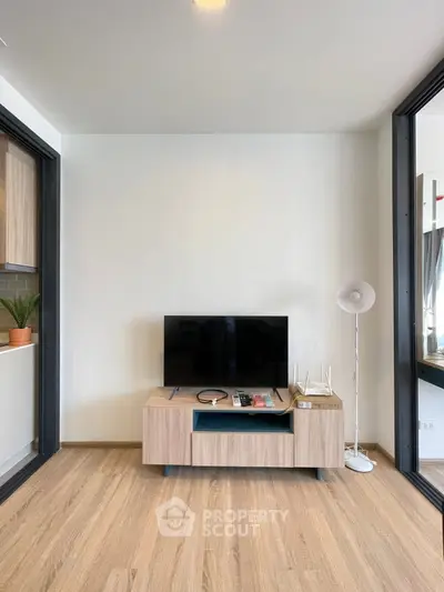 Modern living room with sleek TV stand and floor lamp, showcasing minimalist design and wooden flooring.