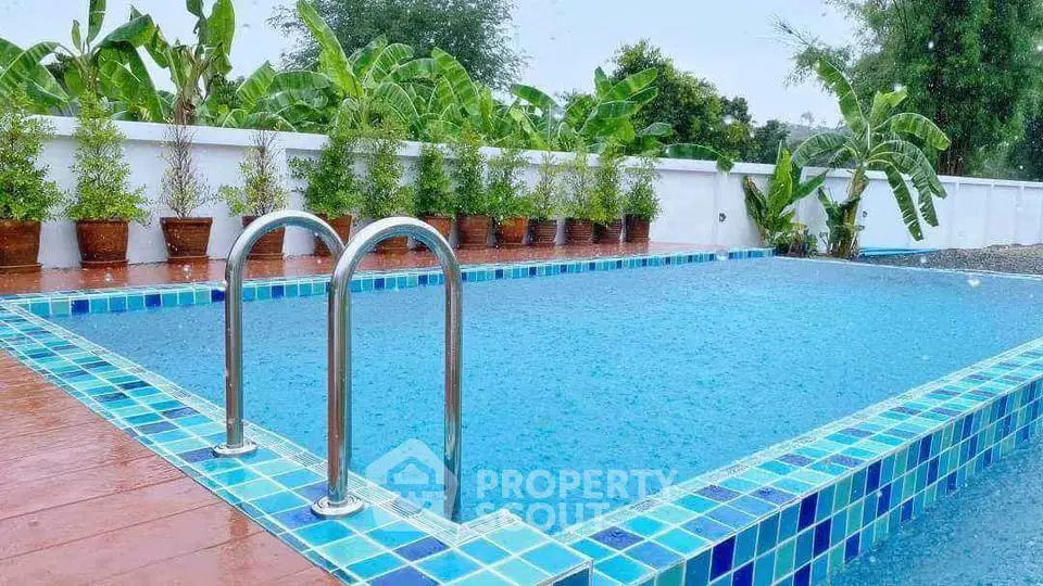 Stunning outdoor pool with vibrant blue tiles and lush greenery, perfect for relaxation and entertainment.