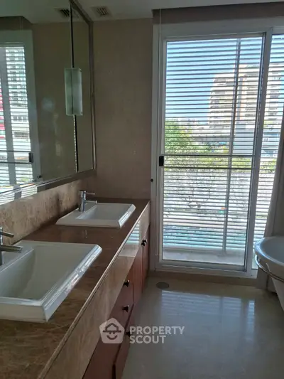 Luxurious bathroom with dual sinks and large window offering city view