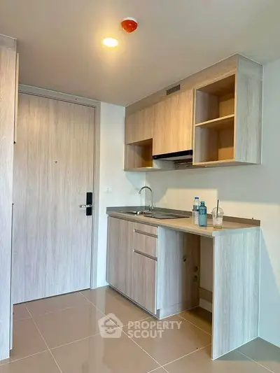 Modern compact kitchen with wooden cabinets and sleek design in a contemporary apartment.