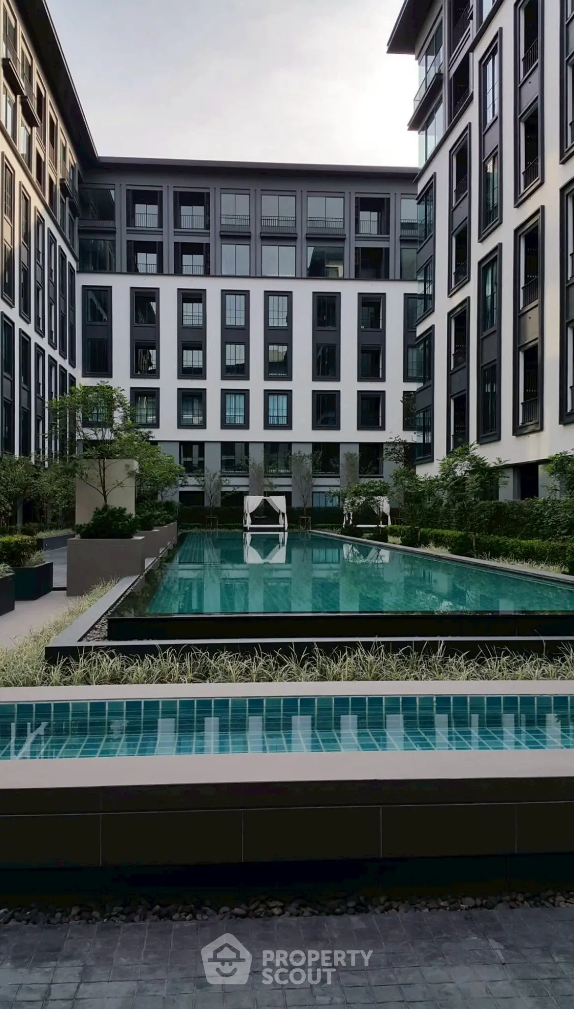 Luxurious modern apartment complex with a stunning pool and elegant architecture.