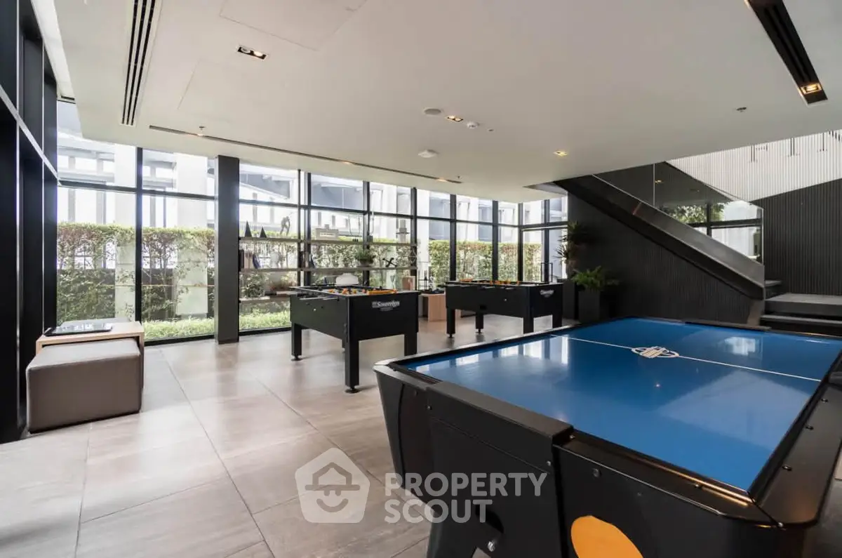Modern game room with air hockey and foosball tables in a stylish building.