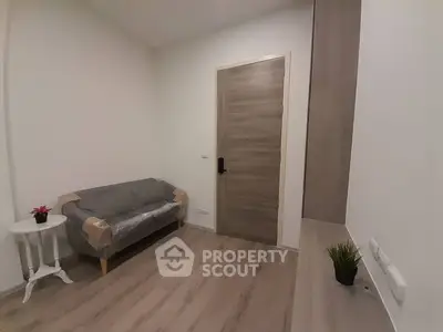 Cozy and modern living room with pristine wooden flooring, fresh white walls, and a comfortable sofa still wrapped for protection, awaiting its new owners.