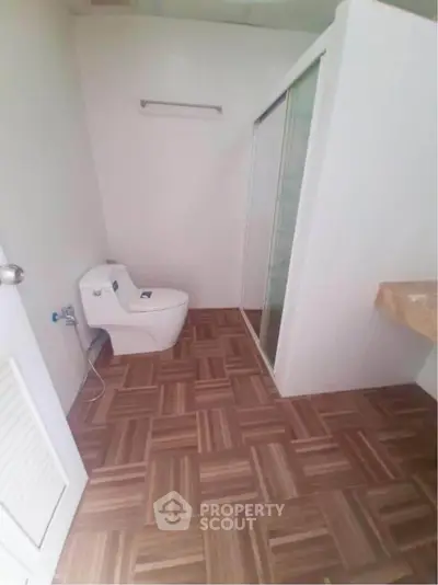 Modern bathroom with wooden tile flooring and glass shower enclosure