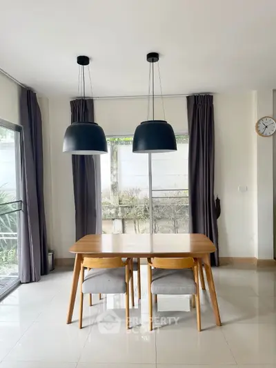 Modern dining area with sleek wooden table, stylish pendant lights, and large windows for natural light.