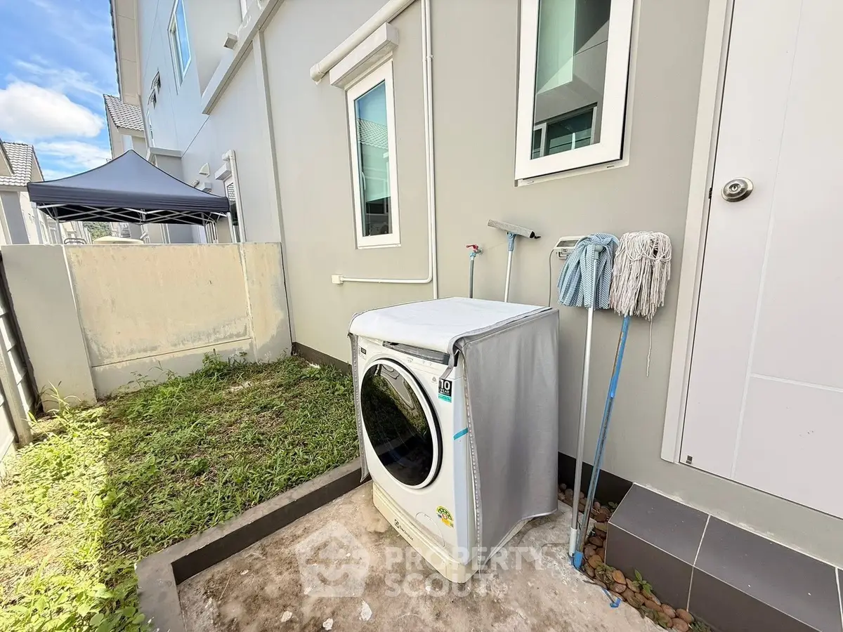 Modern exterior laundry area with washing machine and cleaning tools in a residential property.