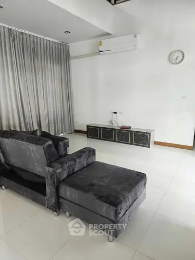 Spacious modern living room with sleek gray sofa and wall-mounted air conditioner.