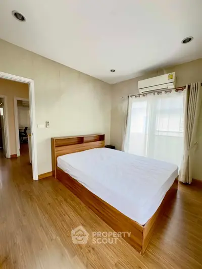 Spacious bedroom with wooden flooring and natural light