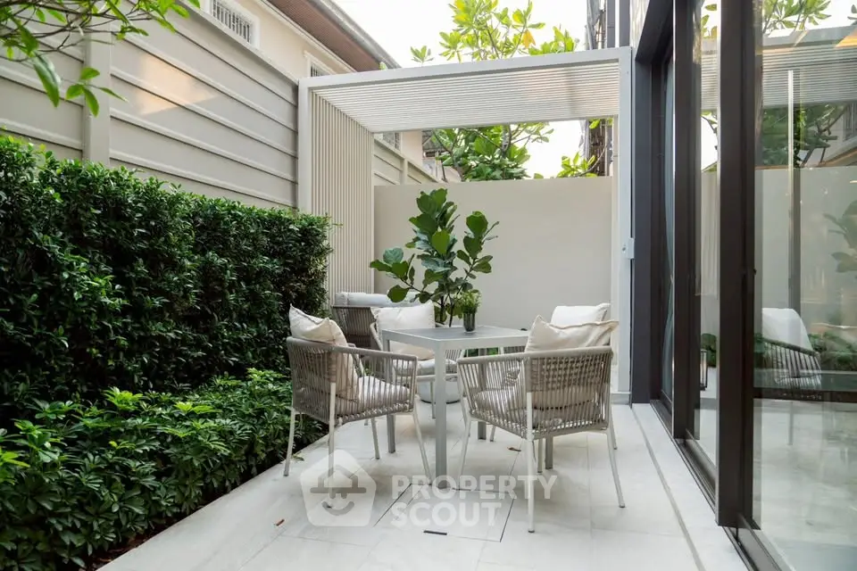 Charming outdoor patio with modern furniture and lush greenery, perfect for relaxation and entertaining.
