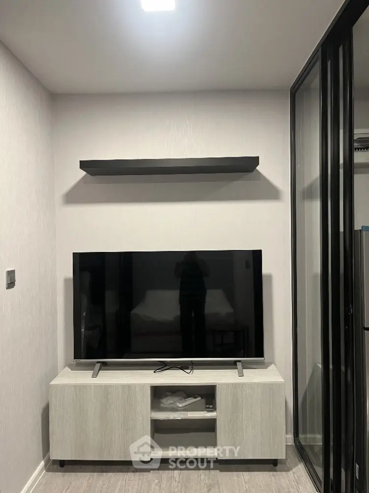 Modern living room with sleek TV setup and glass partition, perfect for urban living.